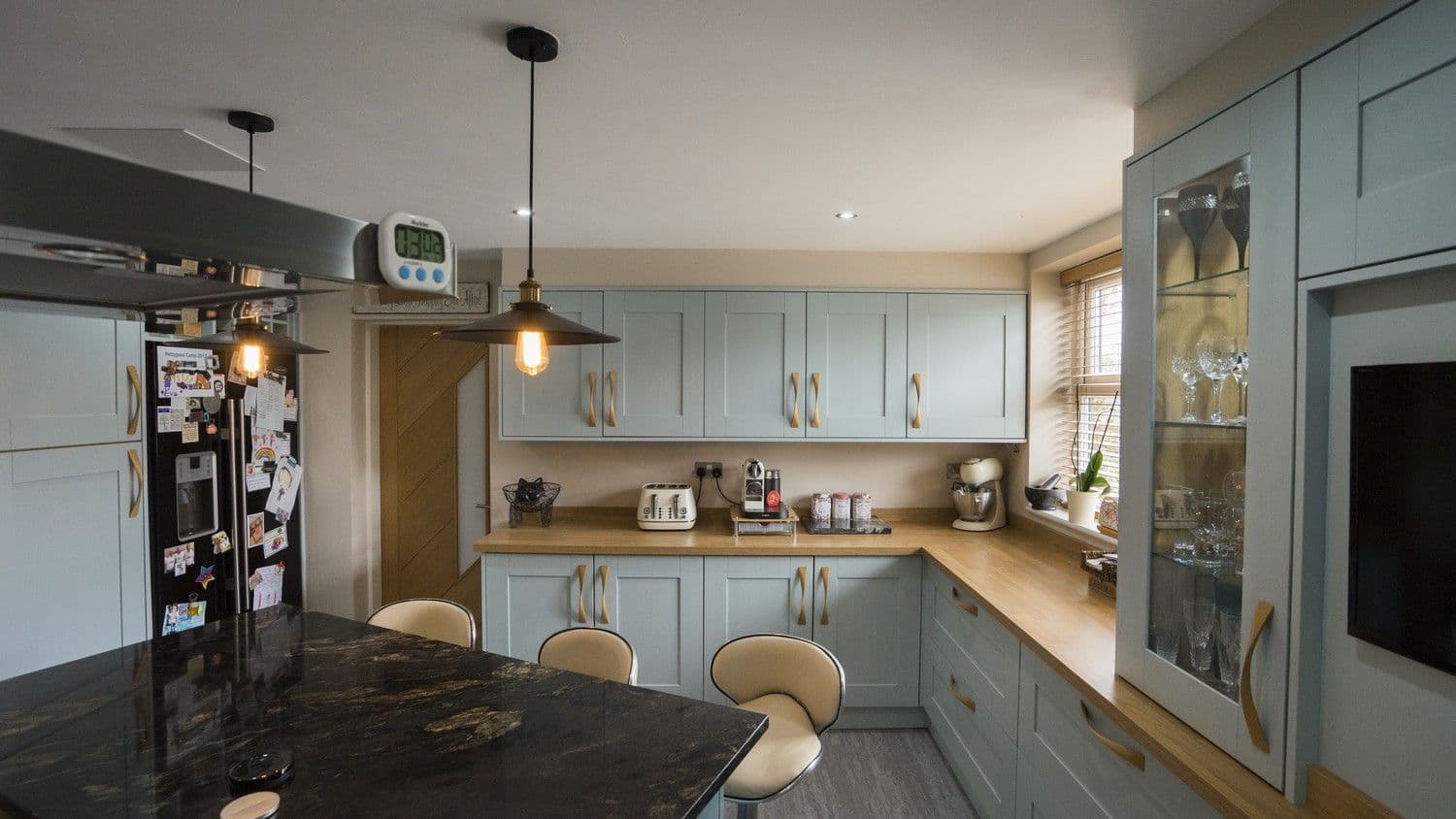 This family kitchen has oak timber worktops around the outer cupboards with matching bespoke oak handles throughout.