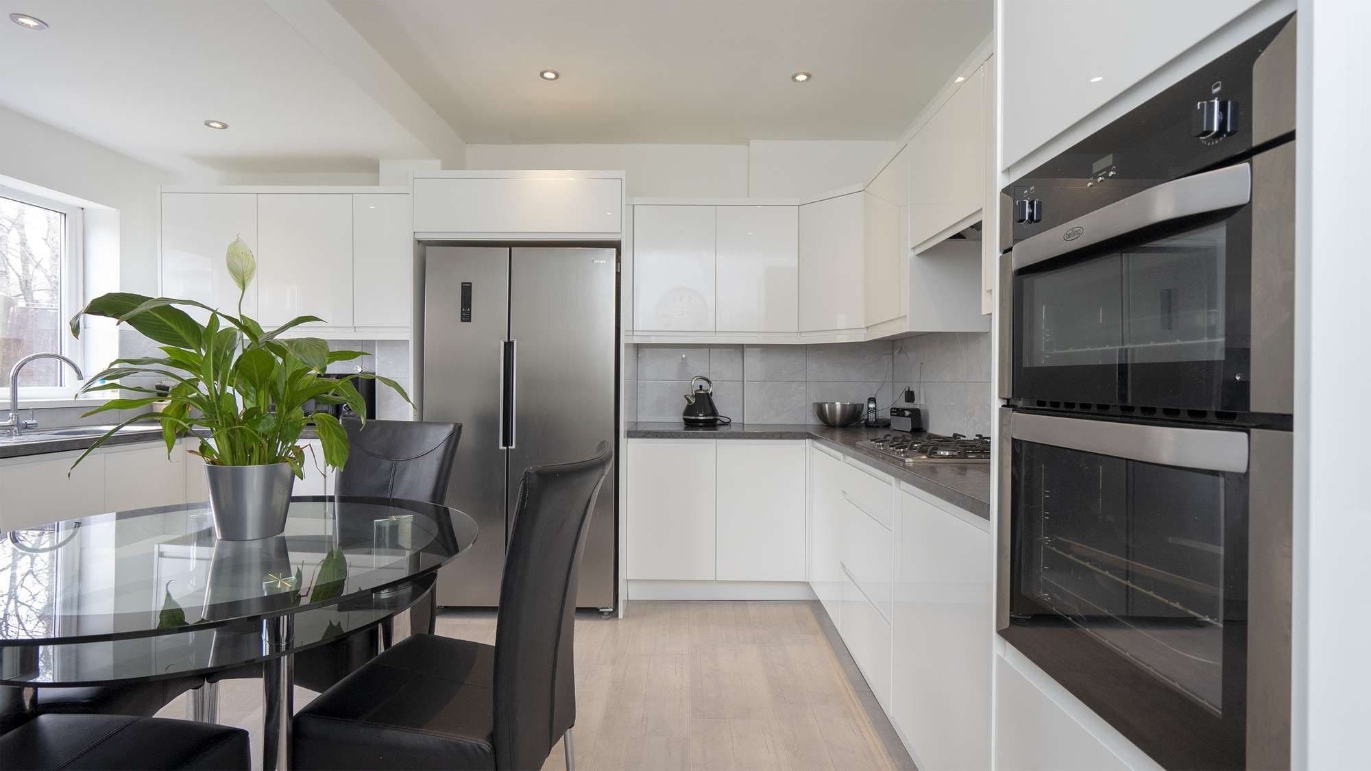 Gloss white handleless kitchen with black worktops and american fridge freezer.
