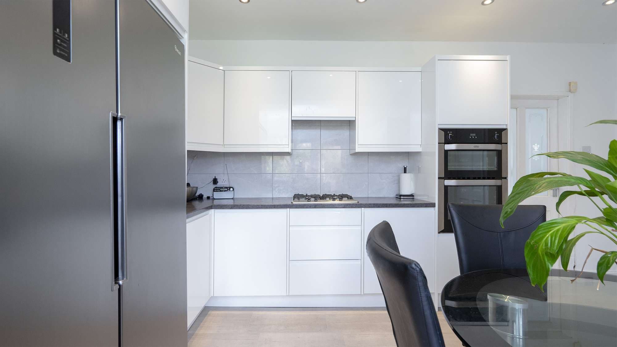 Straight on view of the white gloss cupboards and american fridge freezer.
