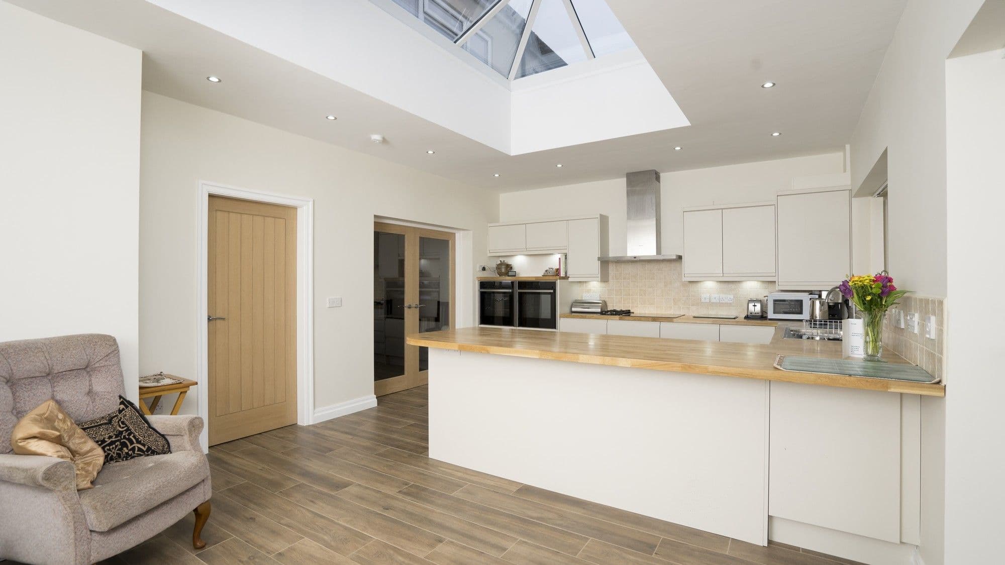 Overview of handleless kitchen in Wavertree, Liverpool featuring gloss cream doors and oak block worktops.