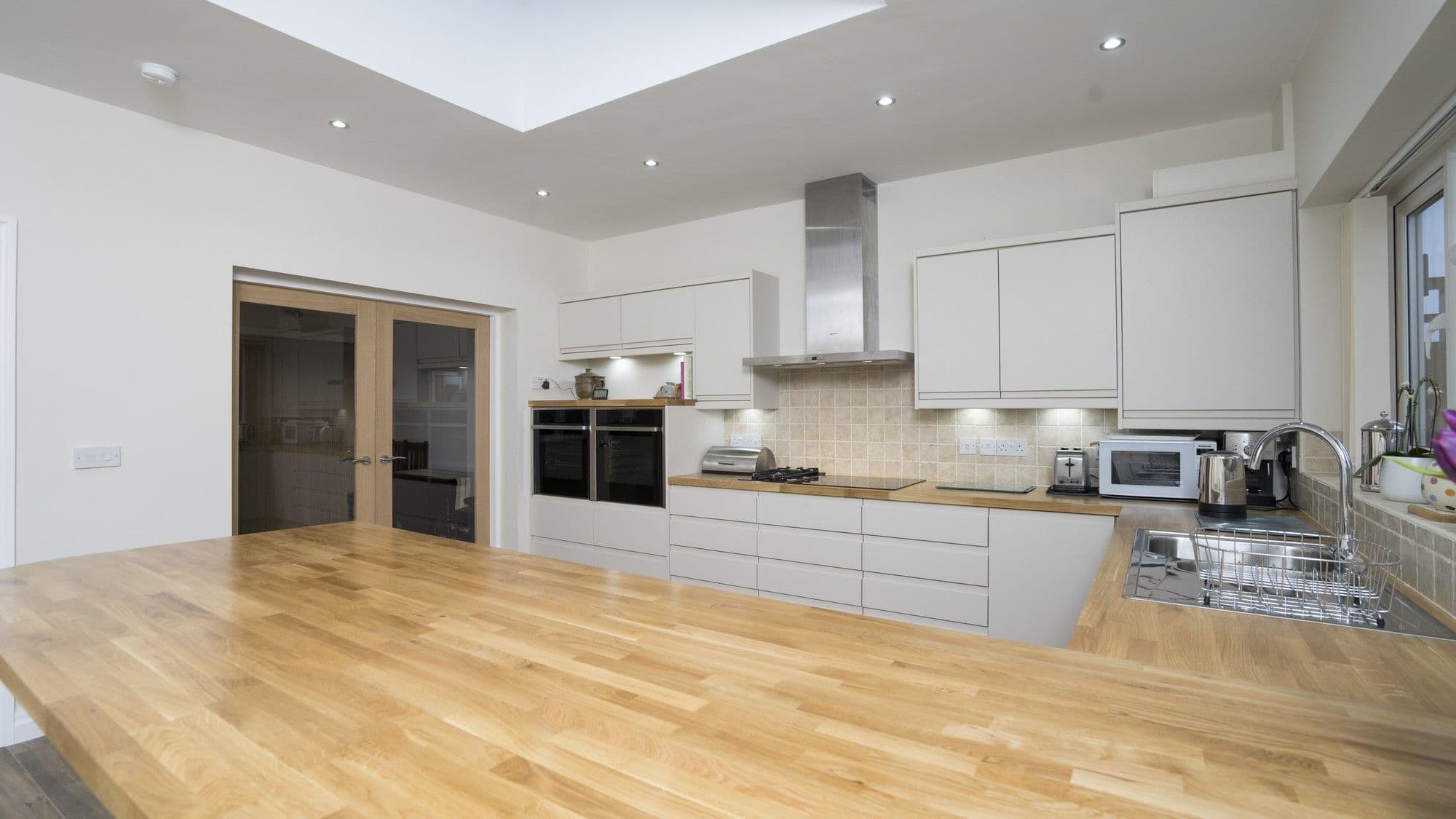 Alternative view of the kitchen with feature under cupboard lighting and stainless steel sink in Liverpool.