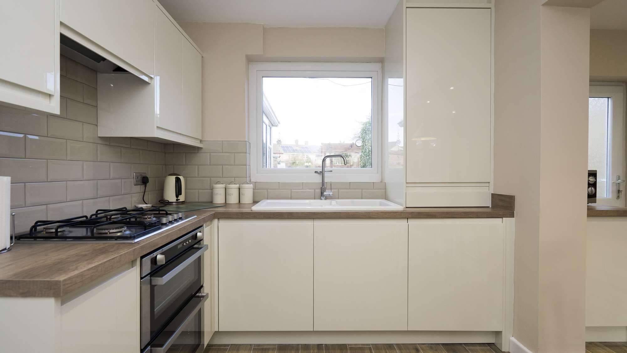 Straight on view of this gloss cream handleless kitchen installed in Warrington, featuring wood worktops and integrated oven.