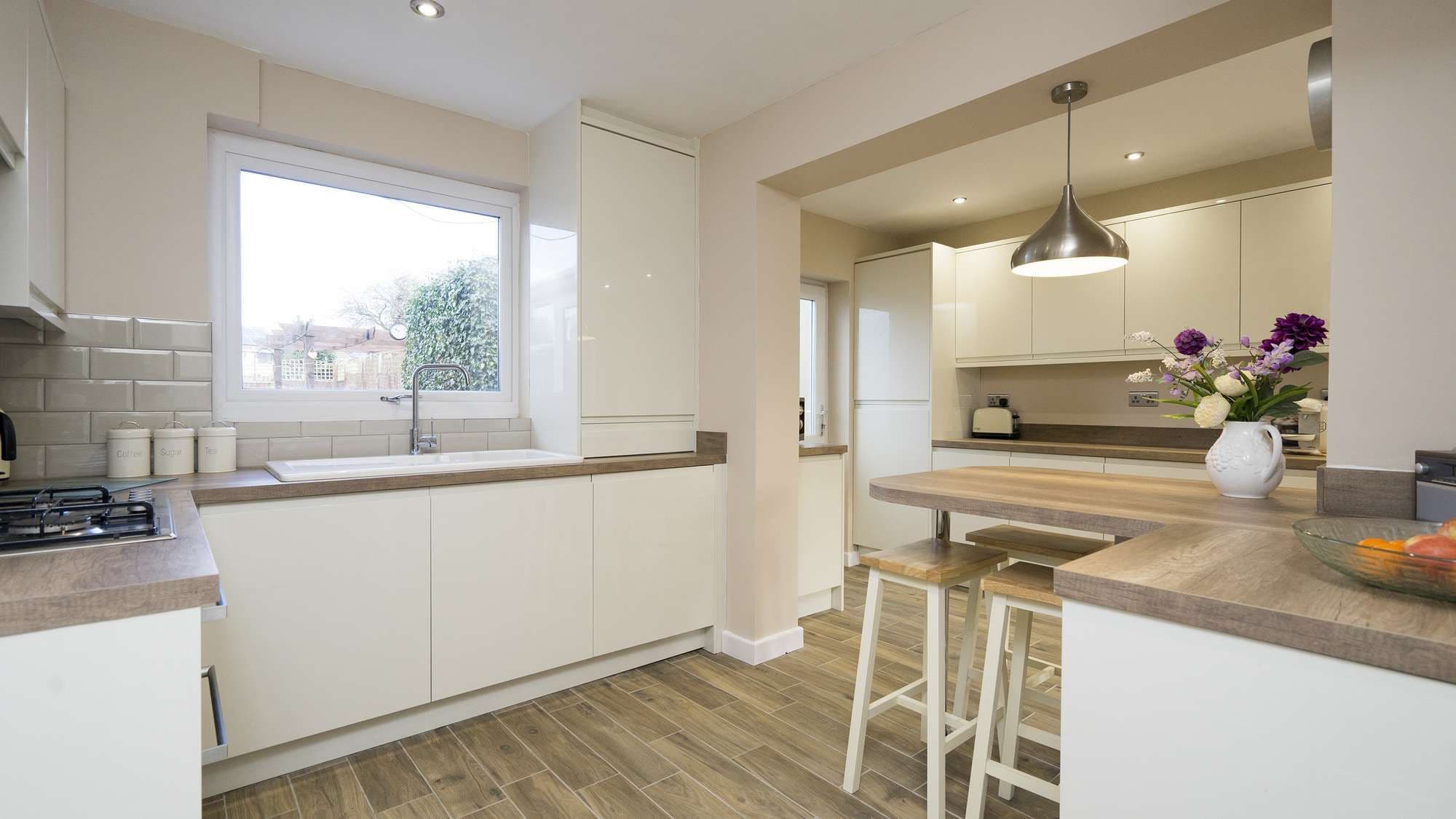Angle shot of this stunning handleless kitchen installation with central peninsular island, bar stools, and lots of storage.