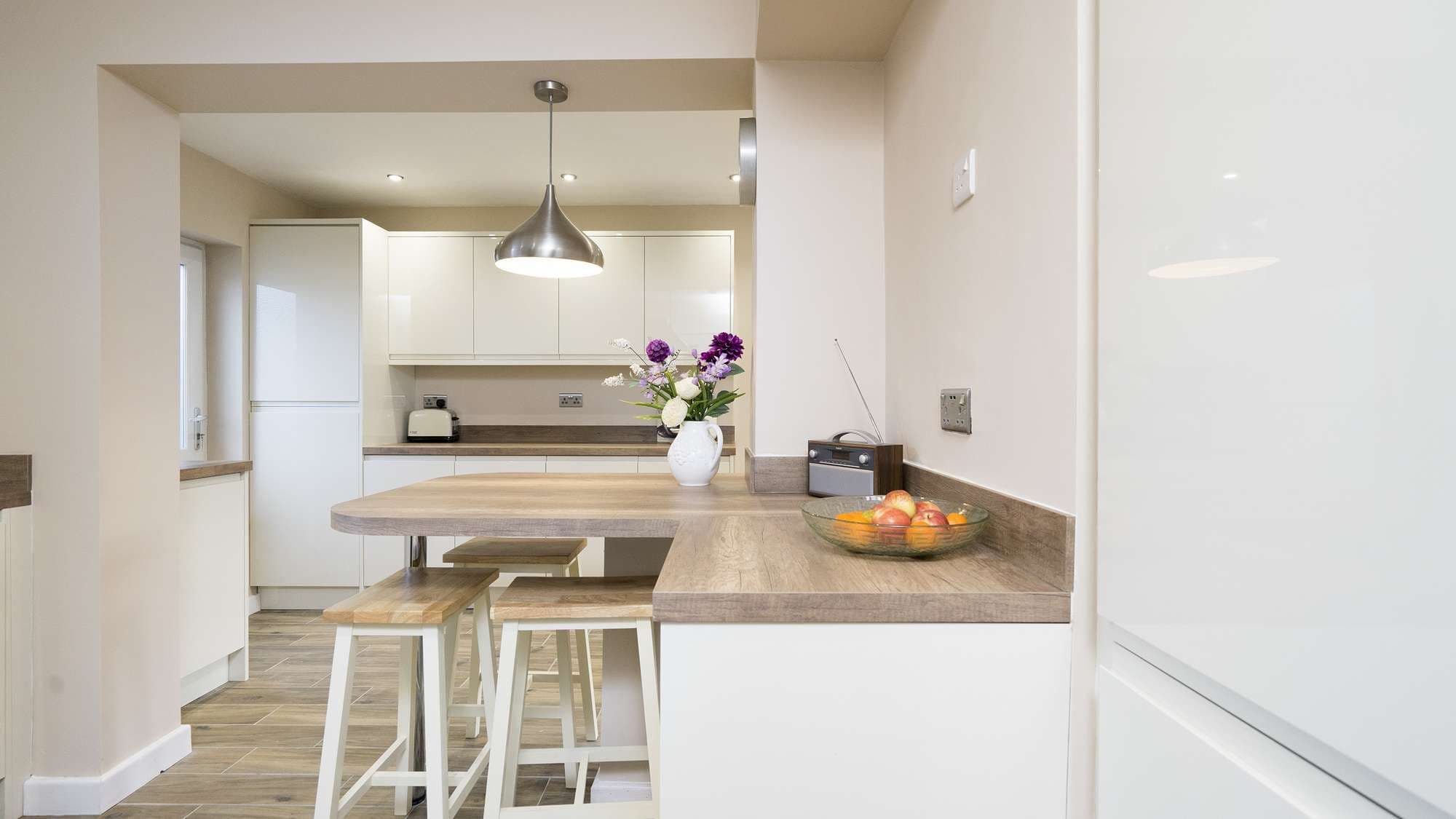 Straight on shot of the wood-grain worktops and gloss cabinets, including an integrated fridge.