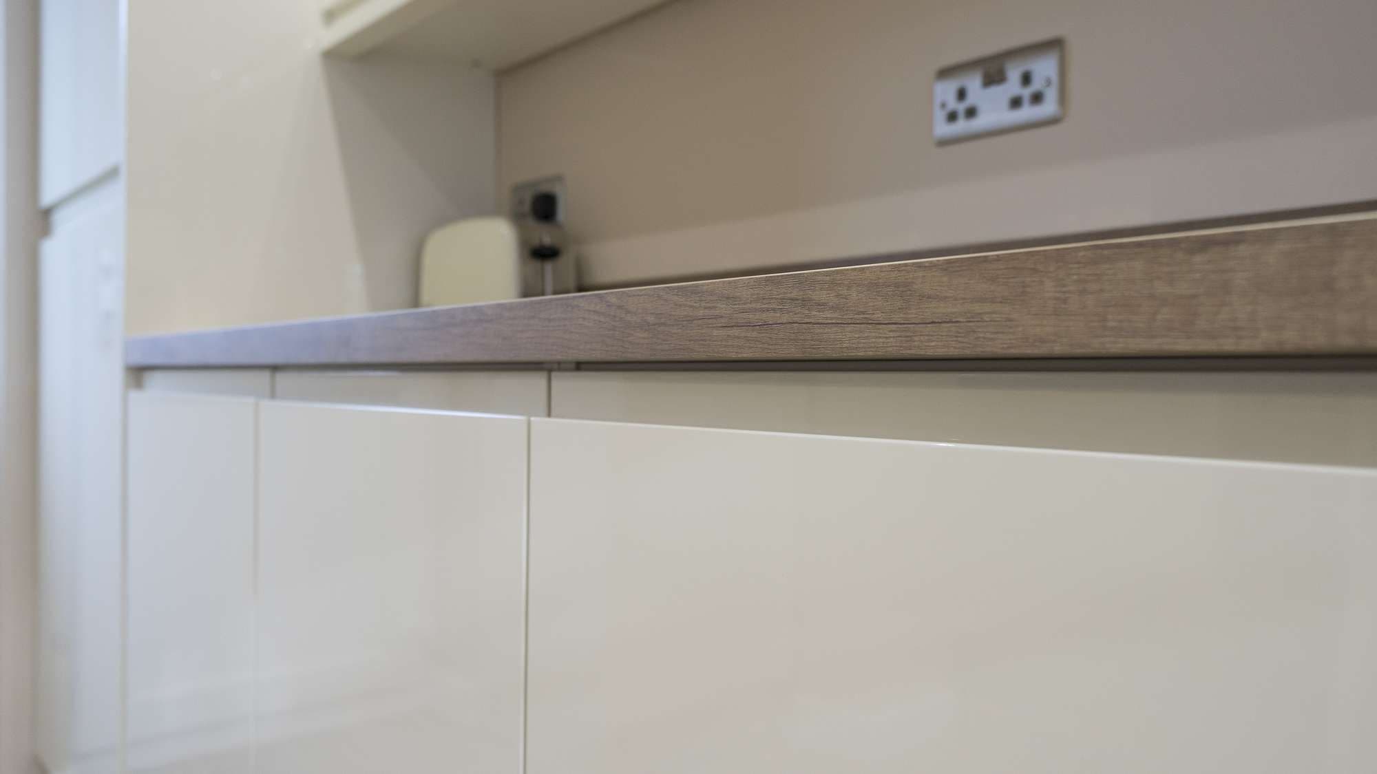Close up of the handle detail on these cream kitchen doors and the end grain on the wooden effect worktops.