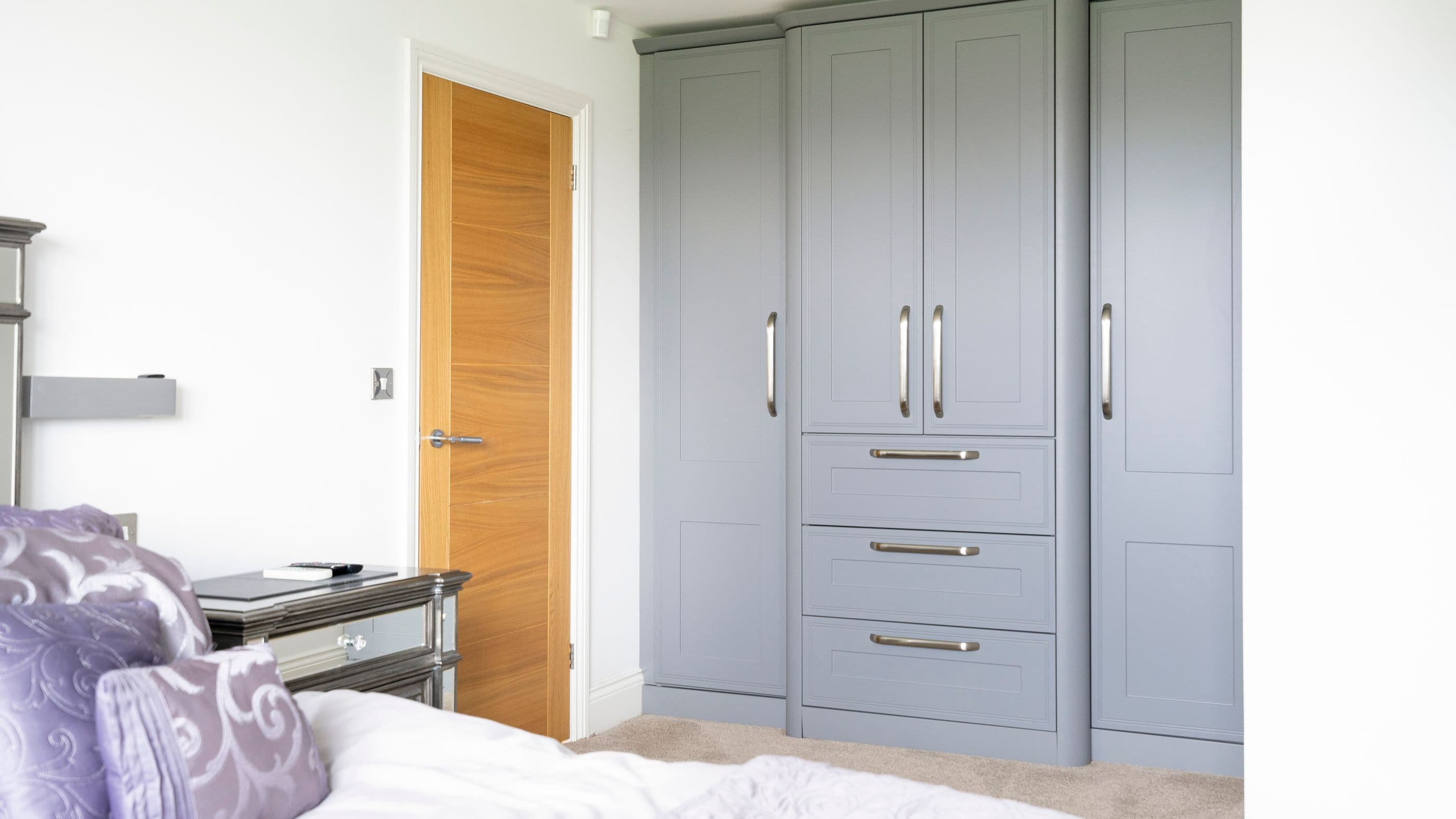 Grey shaker fitted wardrobe with drawers and rounded corner posts.