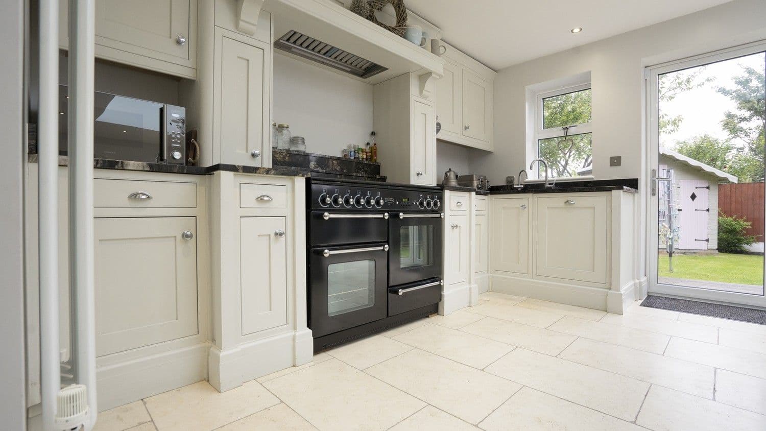 Close up of the cooking area of this kitchen with large range cooker, extractor fan and dual sinks this kitchen has everything needed for preparing for for both family tea time and larger gatherings.