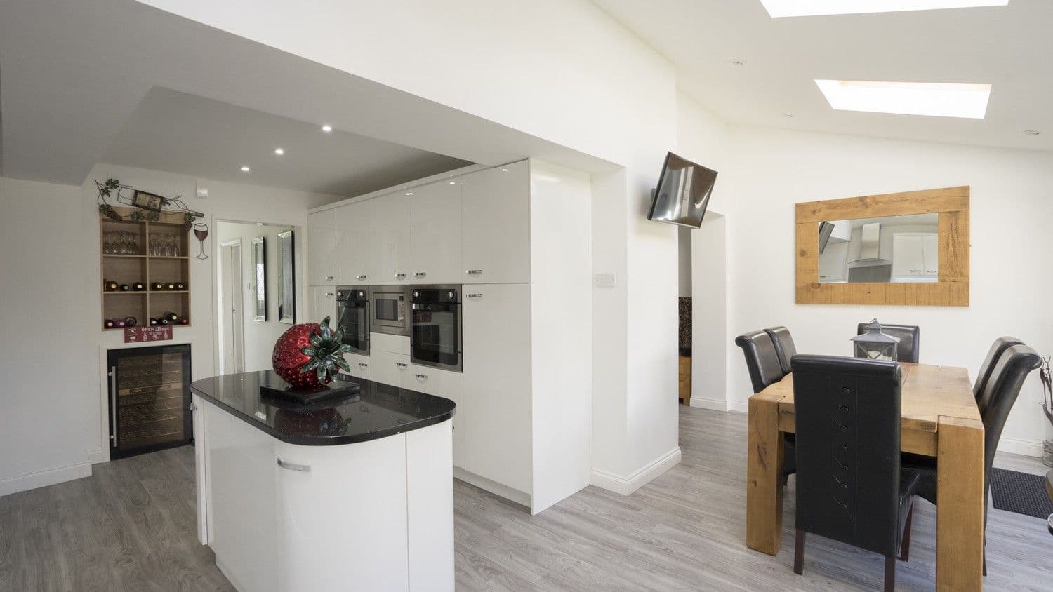 Overview of a white gloss slab kitchen that we supplied to a customer in Kirkby, Liverpool. This kitchen features granite worktops, various cupboard designs and chrome handles.