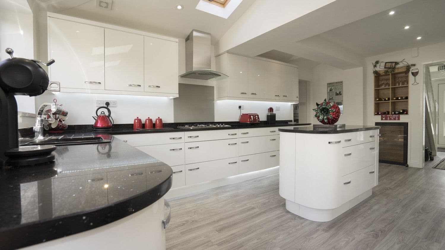 Gloss white kitchen with central island with curved corner cupboards and a large selection of drawers.