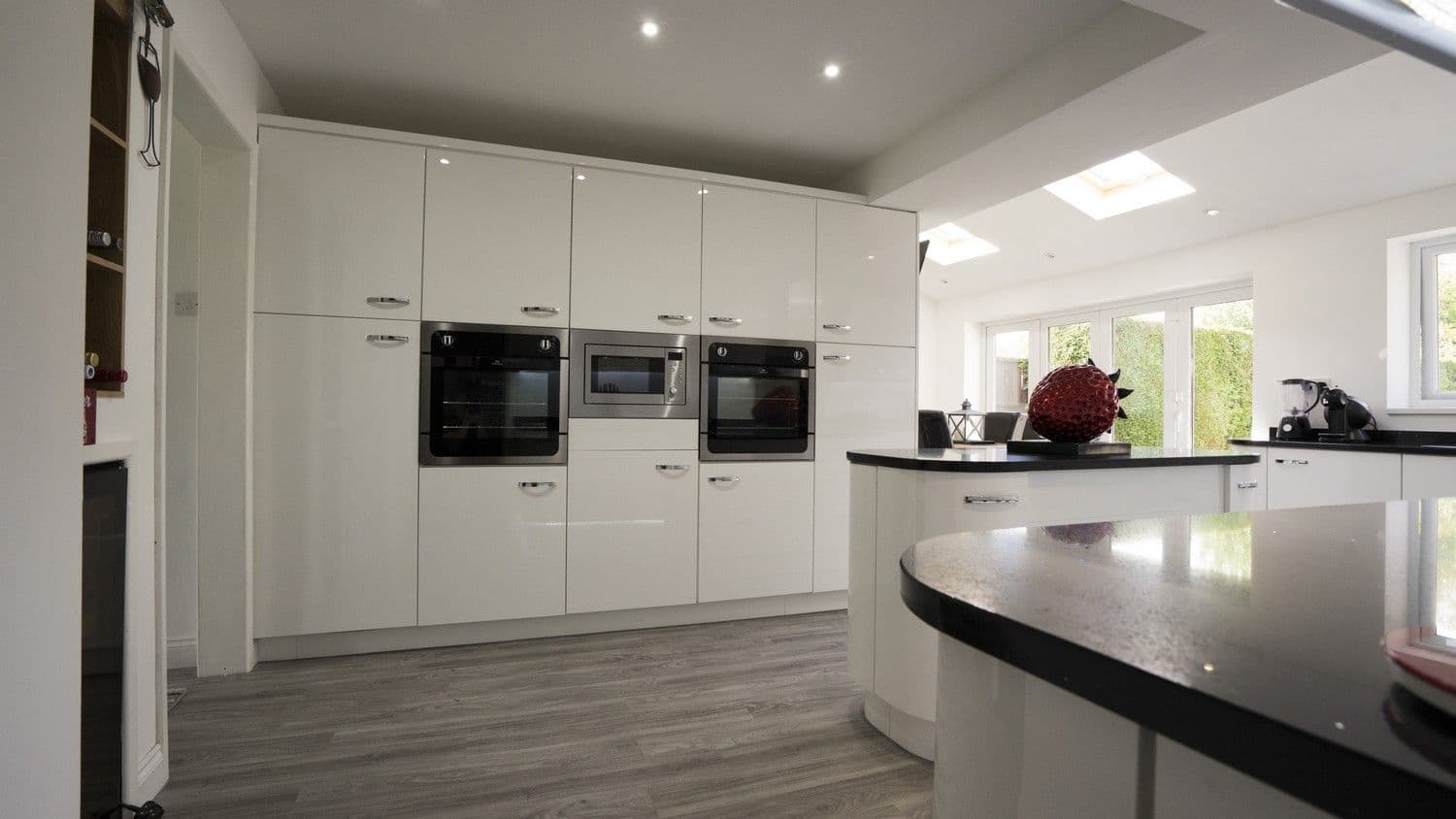 Close up of the floor to ceiling cupboards with integrated appliances, notice the bi-folding doors in the background leading onto the garden.