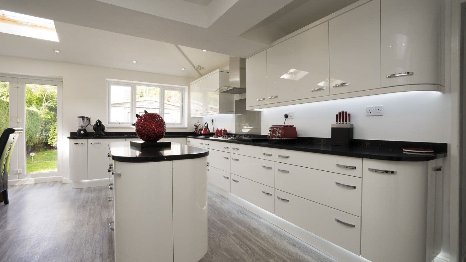 Long run of cabinets featuring curved end units, helping add to the feeling of space within the family kitchen.