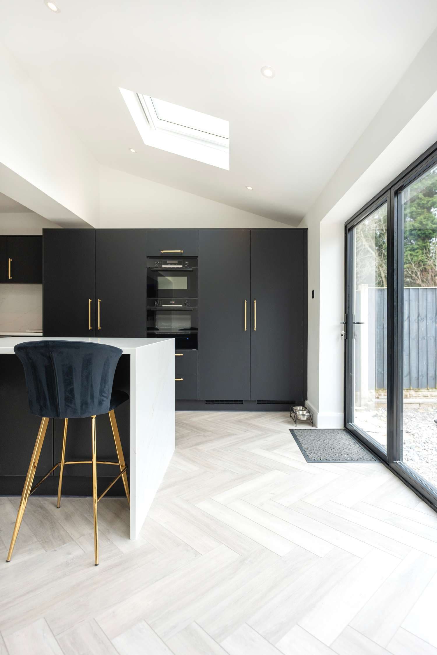 Vertical view of kitchen island and matt black cupbaords