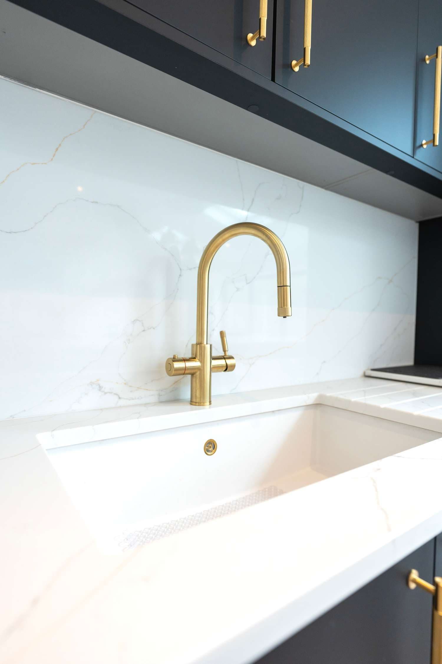 Close up of sink and hot water tap with quartz backsplash