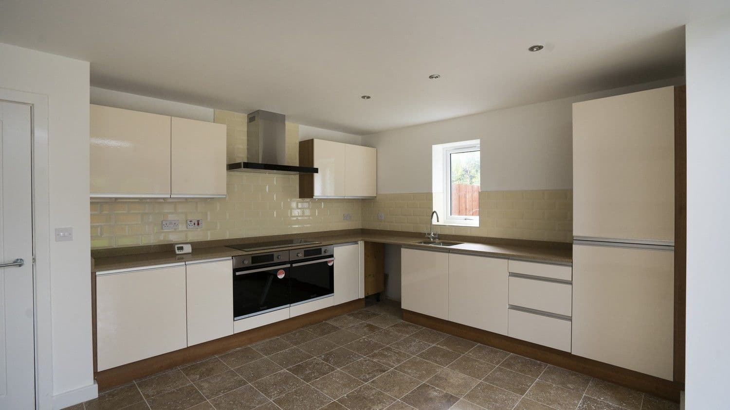 Contemporary kitchen installed in this new build house Liverpool. The kitchen features a unique handle-less design, gloss cream doors and all the modern appliances you would expect from a modern kitchen.