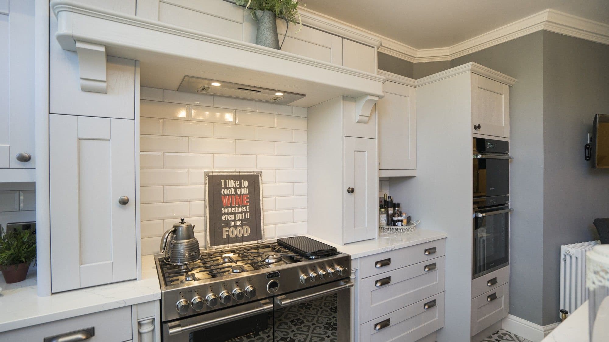View of the range cooker with feature mantel housing the extractor fan. A single oven and microwave have been housed in a separate floor to ceiling cupboard giving plenty of options when it comes to cooking.