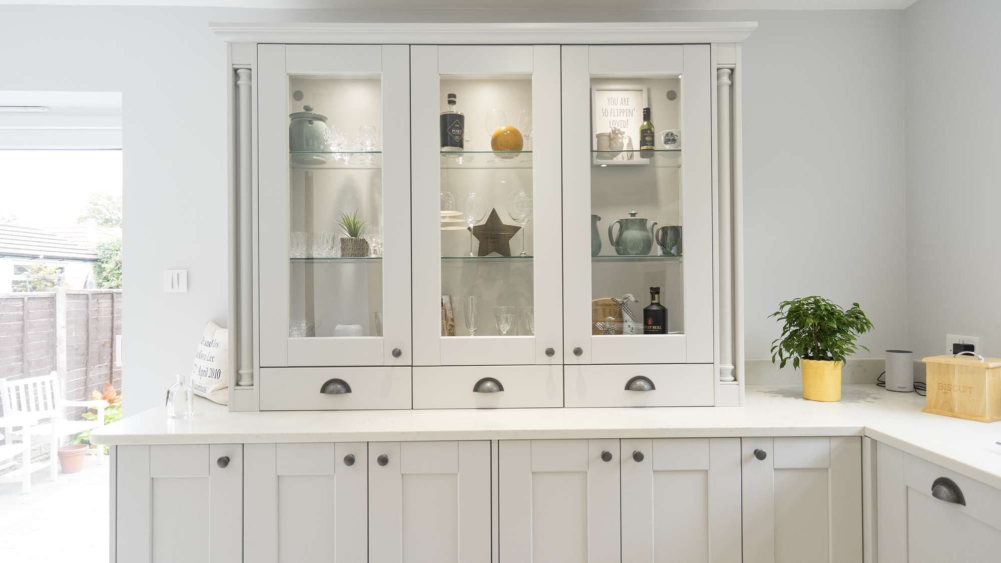 Straight on view of the glass display cabinets with shaker doors, traditional pelmet and decorative newel posts.