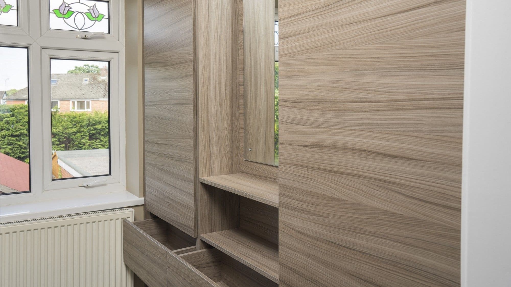 Right hand side of the walk in wardrobe featuring wardrobe doors and a mirror station.