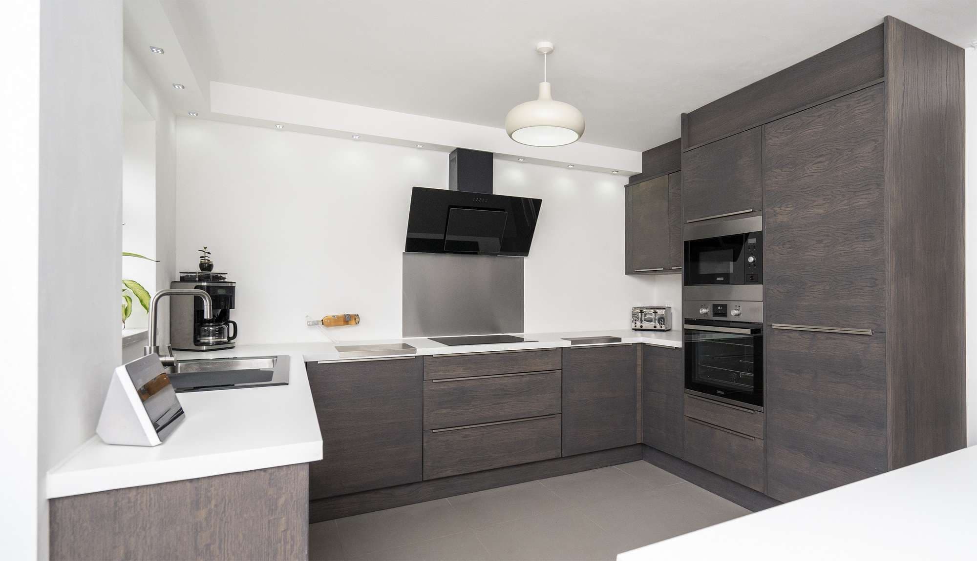 Walnut slab kitchen with slimline stainless steel handles and integrated appliances.