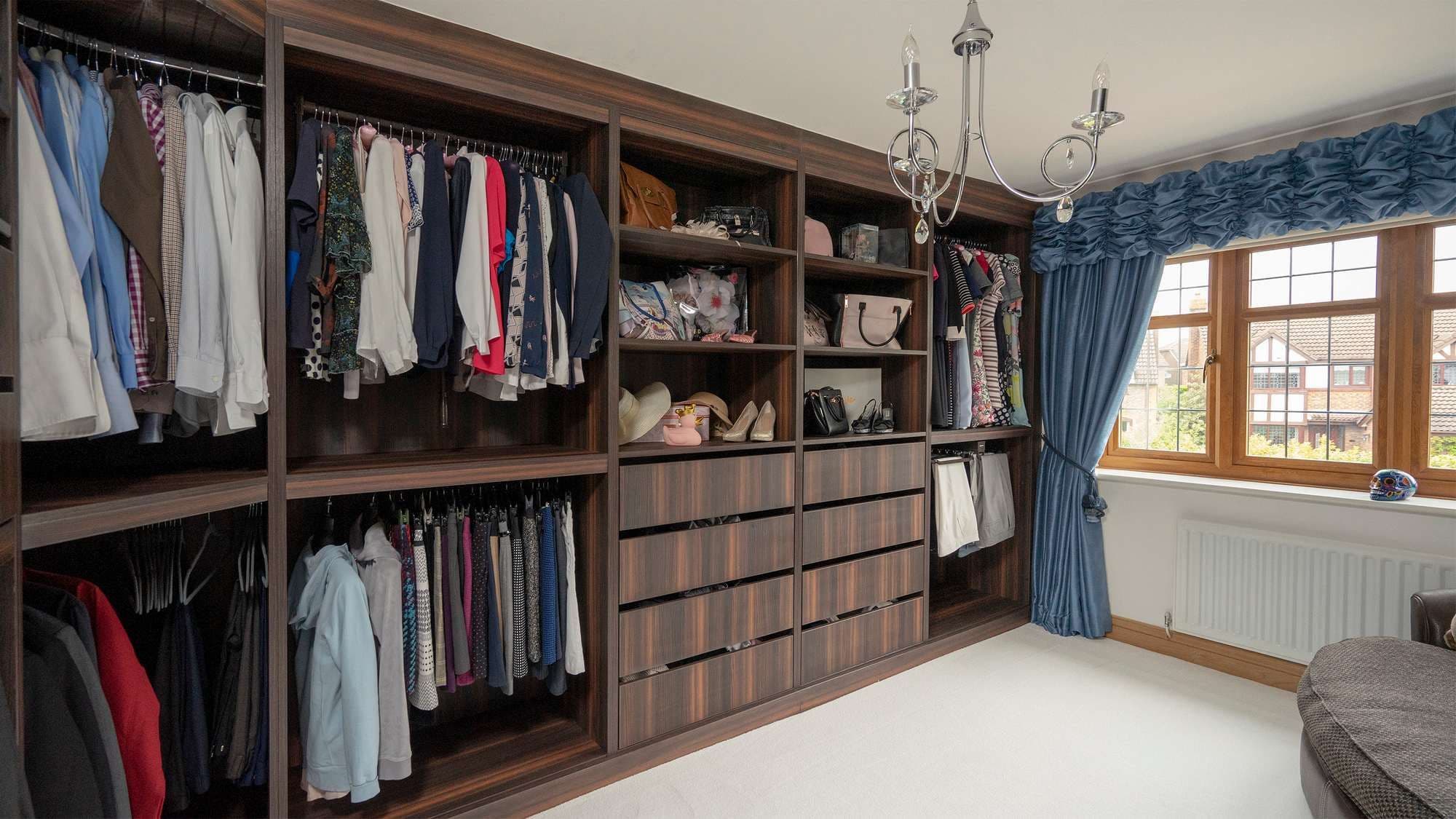 Image showing some of the storage on offer in this stunning walk-in wardrobe featuring clothing rails, central shelving and drawers.