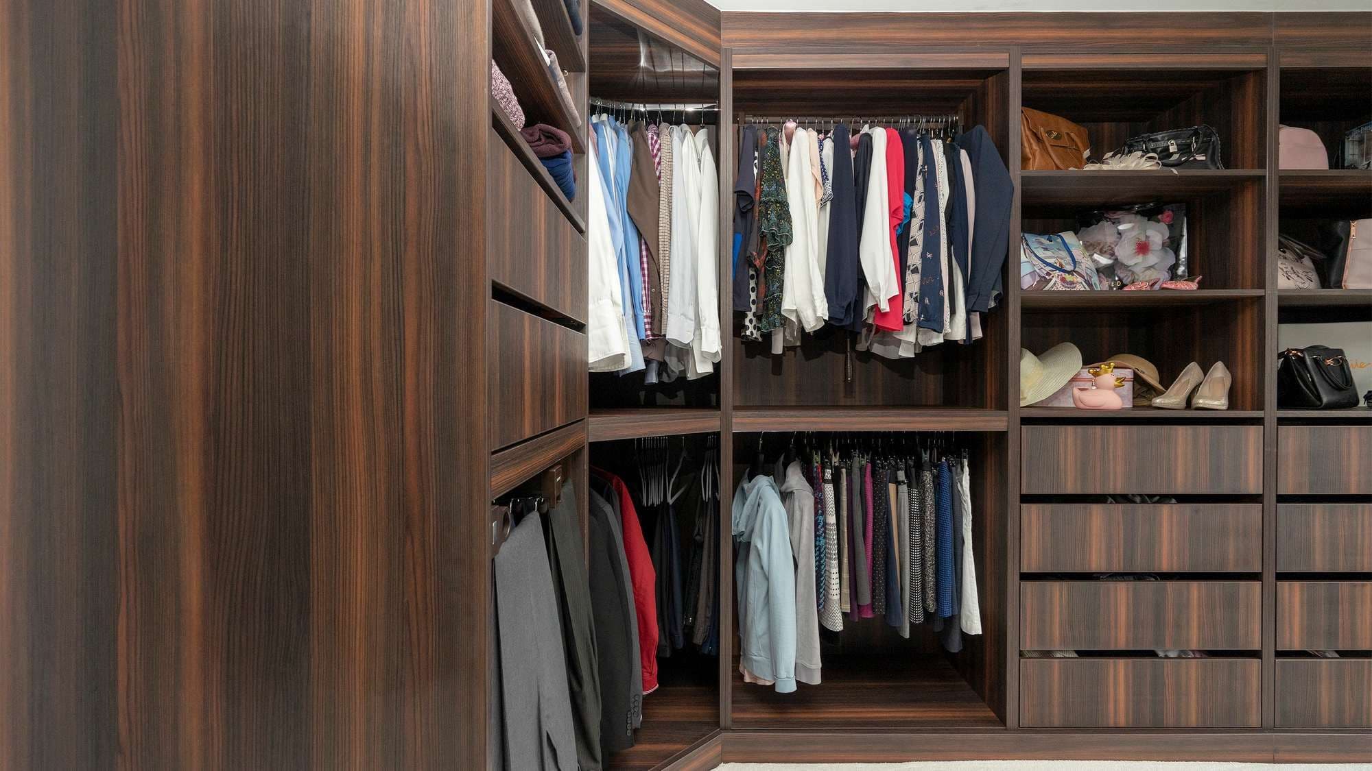Straight on close up detail of the walk-in wardrobe corner finished in a dark walnut wood.