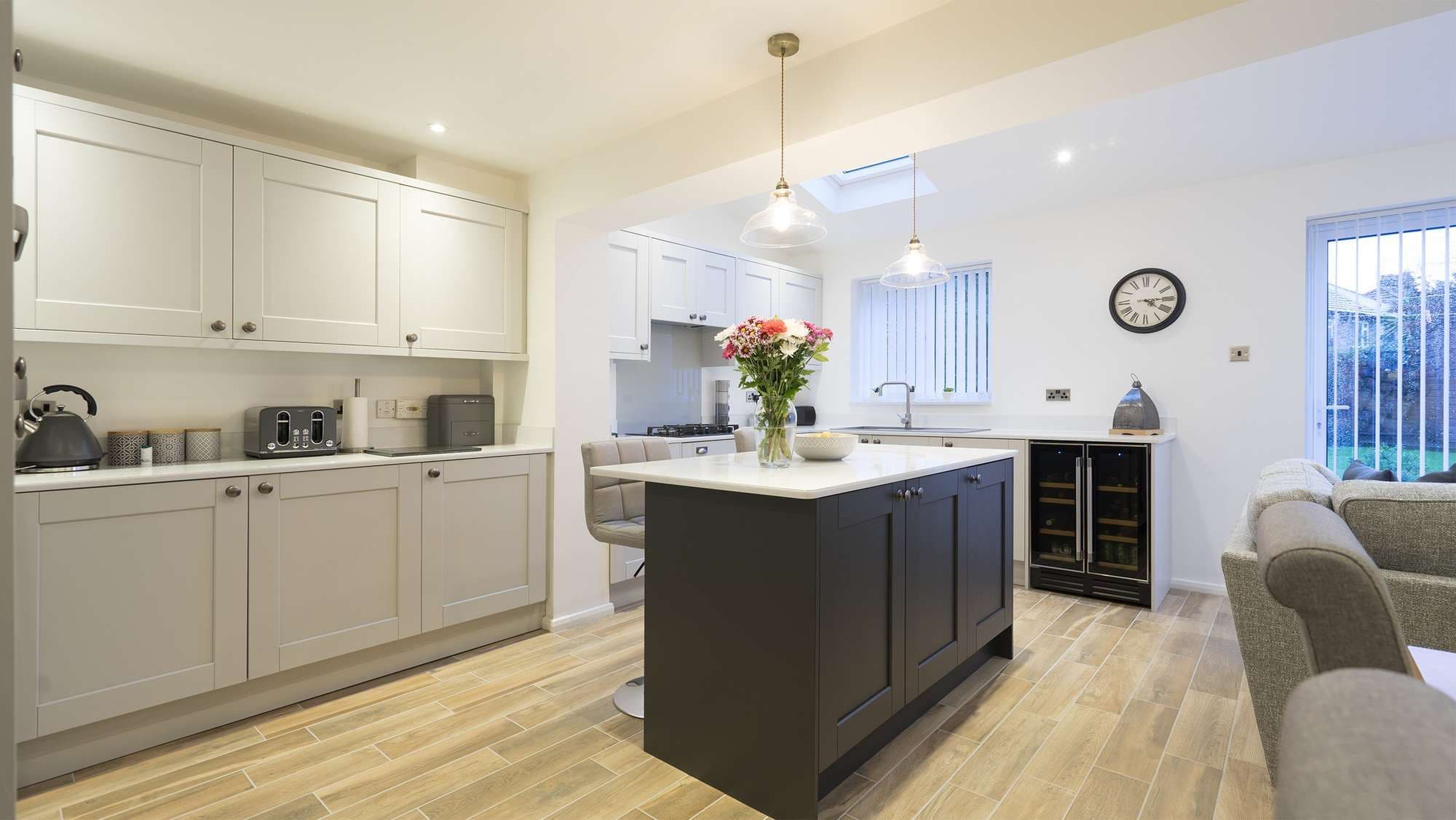 Light grey shaker kitchen with dark grey contrasting island and seating area.